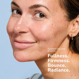 Close-up of a smiling woman with clear skin and freckles showing skincare results